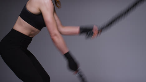 Close-Up-Studio-Shot-Of-Mature-Woman-Wearing-Gym-Fitness-Clothing-Doing-Cardio-Exercise-With-Battle-Ropes-1